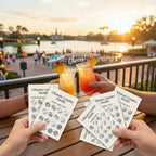 Two people holding drinks and jewelry cards with a scenic background