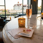 Champagne glass with a candle and playing cards on a marble surface with a cityscape in the background