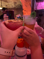Two people holding drinks with a colorful background