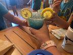 Two people holding blue drinks with lemon slices at a table.